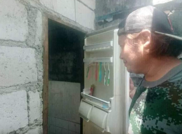 Pintuan ng isang sirang refrigerator, ginamit bilang pinto ng banyo